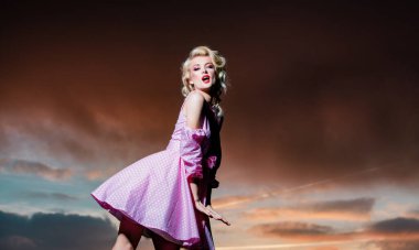 Monroe elbiseli kadın dramatik bir gökyüzünde. Şık bahar kıyafetleri giyen güzel genç bir kadın. Moda elbiseli mankenin portresi