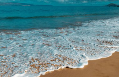 Kumlu sahilde mavi okyanus dalgası. Yaz mevsiminde gün batımında plaj. Plaj manzarası. Tropik deniz manzarası, sakinlik, dinlendirici güneş ışığı