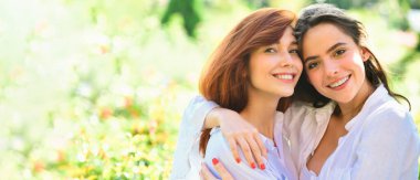 Açık havada kadın kız arkadaşlarla bahar pankartı. En iyi arkadaşlar. Parkta duran mutlu kadın arkadaşlar. Kameraya bakıyorum. Beyaz gömlekli genç kadınlar yeşil alanda yürüyorlar.