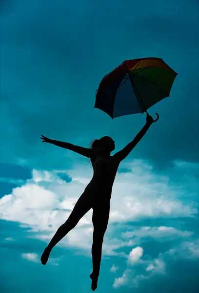 Art ballet. Silhouette of yoga woman with umbrella stretching with pose stretch. Fit fitness athlete girl exercising sports stretches. Cloudy sky background