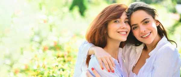 stock image Spring banner with women girlfriends outdoor. Best friends. Happy women friends standing in park. looking at camera. Young women in white shirt are walking on the green field