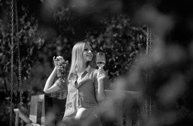 Beyaz üzümden yapılmış el yapımı şarap. Yüzüne bir demet üzüm tutan çok seksi bir genç kadın.