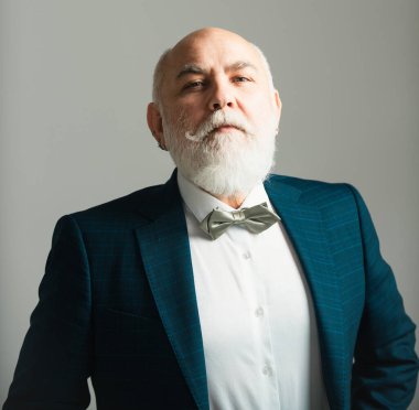 Kıdemli adam. Gri arkaplanda izole edilmiş gri saçlı zarif bir son sınıf öğrencisinin yakın çekimi.