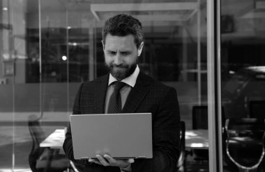 Dışarıda dizüstü bilgisayar kullanan yakışıklı iş adamının portresi.