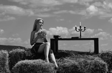 Saman yığını olan kırsal kesimden bir kadın. Moda elbiseli güzel bir bayan. Seksi ve şehvetli bir kadın modeli.