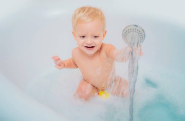 Küçük tatlı sarışın çocuk köpük ve sabun köpüğüyle banyo yapıyor. Sevimli küçük çocuk köpük banyosuyla iyi eğlenceler.