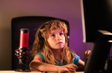 Geceleri bilgisayar kullanan bir çocuk. Karanlık bir odada bilgisayarı olan bir çocuk. Okul, eğitim, online öğrenme konsepti. Klavyede yazan öğrenci.