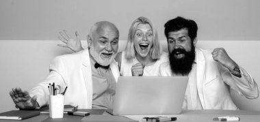 Successful entrepreneurs and business people. Funny excited group of businesspeople working on a laptop at a table in an office