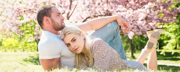 愛の春のカップル バナー 桜の花でリラックスした2人 夫婦恋愛関係 — ストック写真