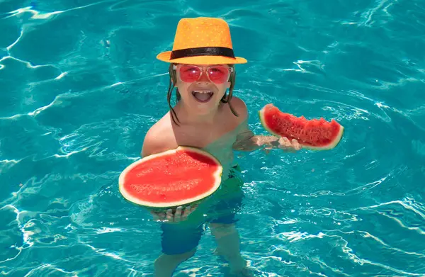 Child eating watermelon. Kid having fun in swimming pool. Summer vacation and healthy lifestyle concept. Kids eat fruit outdoors. Healthy fruits for children