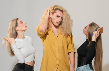 Arka planda saç tarayan çeşitli kadın ve erkek grupları. Çekici, neşeli, seksi, modaya uygun, saç tarayan grup modelleri. Çekici erkek ve kadının saçını tarayan kuaför.