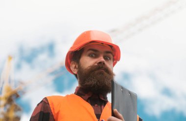 İnşaat alanında miğferli bir işçi poz veriyor. Geliştirme ve yenileme. Zalim bir insan müteahhidi. Üniformalı mühendis.