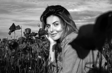 Kırmızı haşhaş tarlasında güzel bir kadının portresi doğanın tadını çıkarıyor. Haşhaş tarlasında genç bir kadın. Bahar kızı