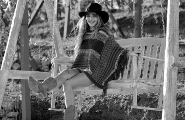 Yazın salıncakta sallanan boho tarzındaki şehvetli hippi kadın, bahar parkında şapka takan genç seksi kız. Özgürlüğün tadını çıkaran ve tasasız hisseden genç bir kadın.