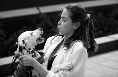 Havalı yaz kıyafetleri içinde güzel bir kadın köpekle dışarıda yürüyor.