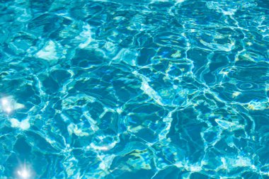 Mavi havuz suyu arka planı. Bulanık şeffaf, durgun su yüzeyi dokusu. Güneş ışığı altında su dalgaları kopyalama alanı ile