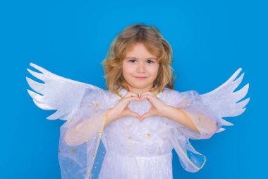 Sevgililer Günü. Mavi stüdyo arka planında melek kanatları olan sarışın şirin çocuk. Mutlu melek çocuk