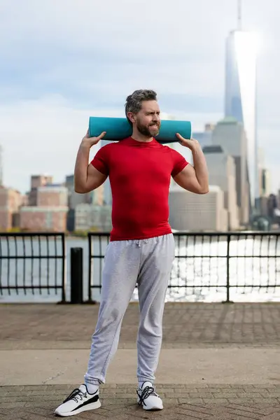 Man in fitness wear workout near Manhattan. Healthy fitness lifestyle. Active senior man is fitness exercising outdoor. Fitness after retirement. Mature retired sportsman doing stretching exercises