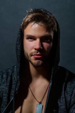 Seksi stüdyo portresi. Stüdyoda şehvetli gey. Seksi, genç ve şehvetli görünümlü bir eşcinsel portresi. Yakışıklı, kaslı ve seksi adam. Erkeksi seksi surat. Erkek güzeli. Kapüşonlu adam kameraya bakıyor.