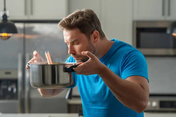 Man cook cooking at kitchen. Chef cook man prepares a dish with food in saucepan. Menu recipe healthy food. Man cook food in modern kitchen. Mature man standing in kitchen, preparing food