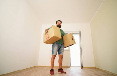Taşınma gününde karton kutu taşıyan bir adam. Bir daireye taşınmak için karton kutular yükleyen teslimatçı.