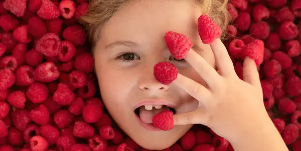 Summer fruits. Cute little girl eats raspberries berries. Kid eating vitamins. Close up face