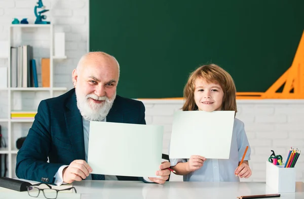 祖父と幸せな子供は紙の板紙を保持します 上級教師は学ぶのを助ける 小学校 — ストック写真