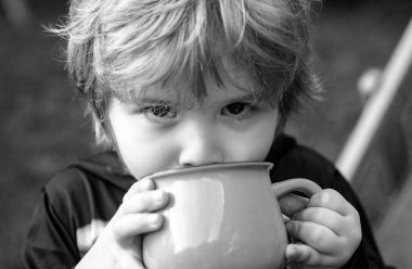 Bir şey içen çocuk. Küçük çocuk temiz havada eğleniyor. Doğada gülümseyen çocuk portresi