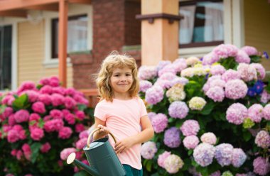 Portrait of cute little boy with water can in garden