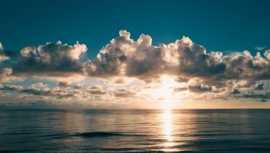 Deniz batımında bulutlu gökyüzü, okyanus sahilinde gün doğumu. Gün batımından sonra gökyüzünde gün batımı manzarası. Gökyüzüne ve denize karşı farklı renkte bulutlarla gün doğumu