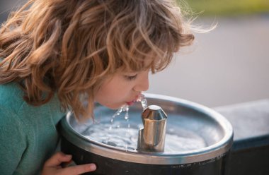 Parktaki musluktan ya da sudan su içen çocuk portresi. İçki içen çocuk portresi. Susamış çocuk