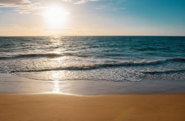 Gün batımı. Kumlu sahilde mavi okyanus dalgası. Yaz mevsiminde gün batımında plaj. Plaj manzarası. Tropik deniz manzarası, sakinlik, dinlendirici güneş ışığı