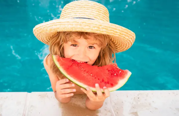 Kid eats watermelon in the pool. Cute boy eating slice of red watermelon on the beach, happy caucasian boy watermelon against the blue water