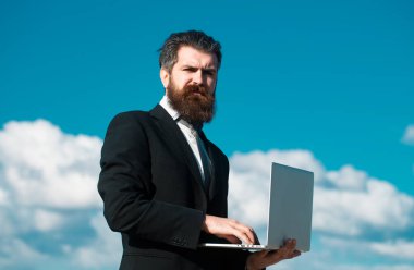 Dizüstü bilgisayarı olan bir iş adamı, açık havada gökyüzü