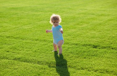 Yeşil çimlerde poz veren sevimli erkek bebek. Sağlıklı çocuk