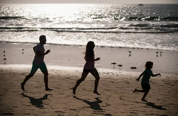 Silhouettes of fitness family running near sea