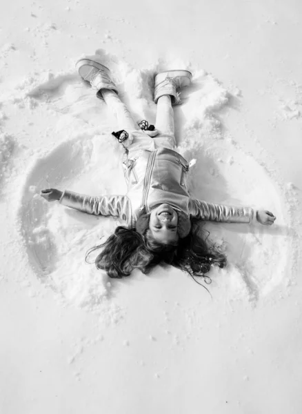 Snow angel made by a kid in the snow. Child girl playing and making a snow angel in the snow