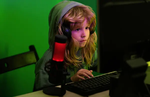 Child gamer playing video game. Child plays a video game on the pc computer screen. Gamer play computer games. Neon lighting. Little hacker, young programmer