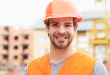 Construction worker man in work clothes and a construction helmet. Portrait of positive male builder in hardhat working at construction site