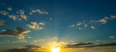 Gün batımı ya da gün doğumu. Dramatik görkemli gün batımı. Gökyüzü bulutlu ve gökyüzü aydınlık arka planda. Farklı şekillerde bulutlarla gün doğumu. Sakin gün batımı gökyüzü ve bulutlar arasında güneş