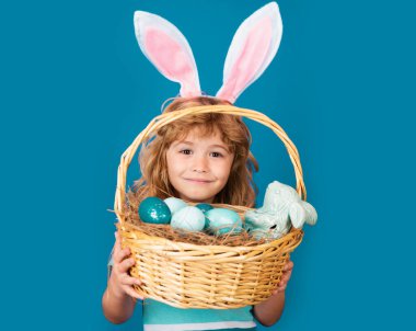 Paskalya sepeti olan çocuk mavi arka planda izole edilmiş. Mutlu Paskalyalar. Paskalya tavşanı çocuklar