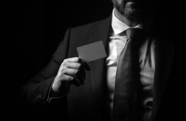 Kredi kartı sahibi bir iş adamı. Elinde boş bir kredi kartı modeli var. Kredi kartı el ele tutuşmanın şablonunu oluşturur. Plastik banka kartı. İşletme markası siyah