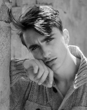 Genç adam kameraya bakıyor. Kendine güveni olan yakışıklı adam.