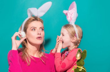 Anne ve kızı Paskalya 'yı kutluyor. Tavşan kulaklı çocuk ve anne gülüyor ve eğleniyorlar.