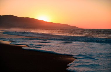 Günbatımı ve okyanus ile soyut bir arkaplan. Deniz yüzeyinin altında büyük sarı güneşli bir gün batımı. Sakin okyanus, gün batımında gökyüzü ve bulutların arasında güneş. Sakin okyanus ve gökyüzü arka planı
