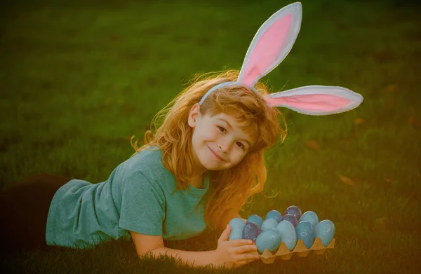 Kids boy in rabbit costume with bunny ears hunting easter eggs. Easter bunny children