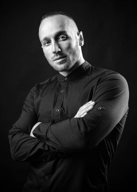 Çapraz kollu ciddi bir adam içeride poz veriyor. Moda erkek modeli.