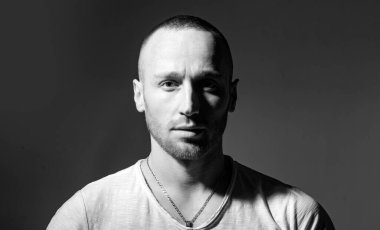 Kızıl sakallı, sakalsız, vahşi bir adam koyu gri arka plan stüdyo fotoğrafında izole edilmiş. Güzel mavi gözlü, kameraya bakan yakışıklı kızıl adam. Alışılmadık erkek görünüşü