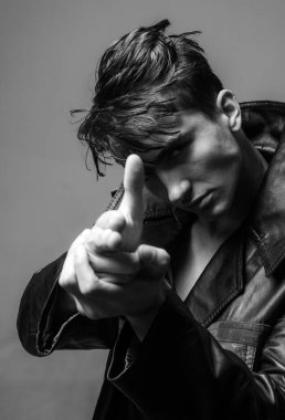 Ciddi, acımasız, kendine güvenen yakışıklı bir adam. Stüdyo moda portresi. Gri duvara dayanmış yakışıklı bir adamın portresi.