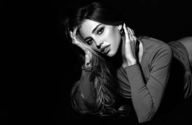 Siyah arka planda ışığı olan şehvetli bir kadın. Karanlıkta güzel bir kadın yüzü. Şefkatli ve baştan çıkarıcı bakışlar. Moda sanat stüdyosu portresi. Siyah stüdyoda şehvetli, baştan çıkarıcı pozlar veren seksi bir kız.